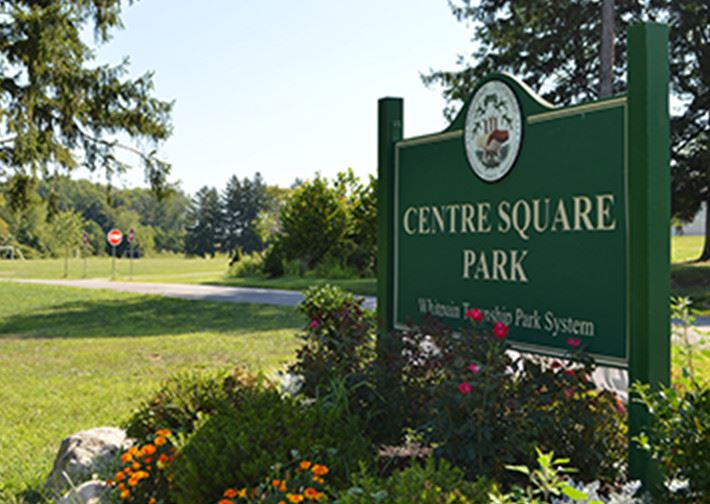 Sign and landscaping with park in background